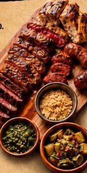 Tábua de churrasco com cortes fatiados, farofa e chimichurri